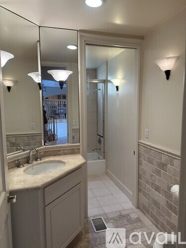 A bathroom with a sink, mirror, and a shower.