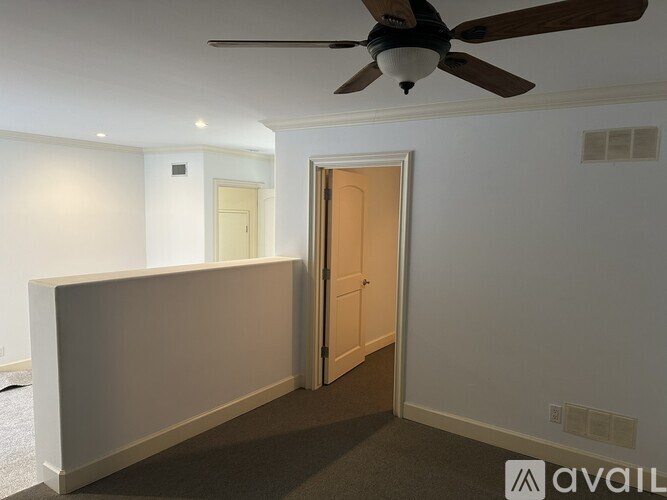 A room with a ceiling fan and a door leading to another room.