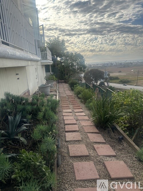 A garden pathway made of bricks leads to a house.