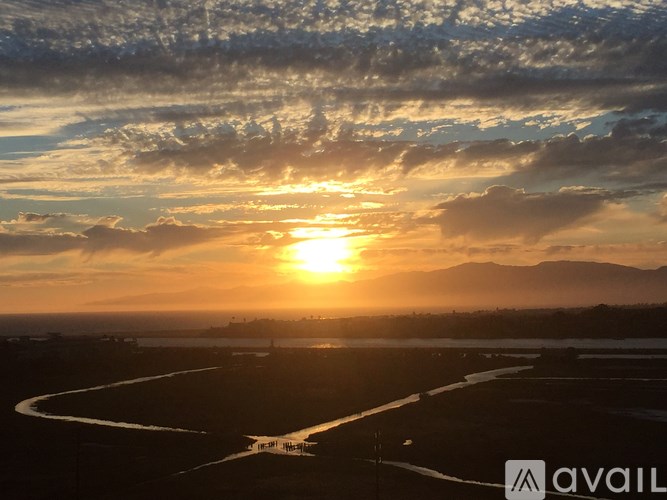 A sunset over a landscape with a river and mountains in the distance.