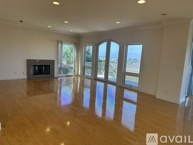 A spacious living room with a fireplace and large windows overlooking the ocean.