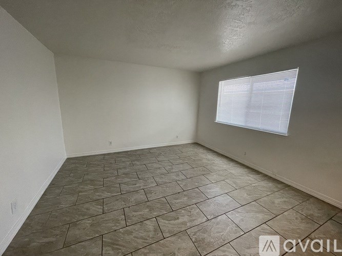 A room with a window and tiled flooring is available for rent.