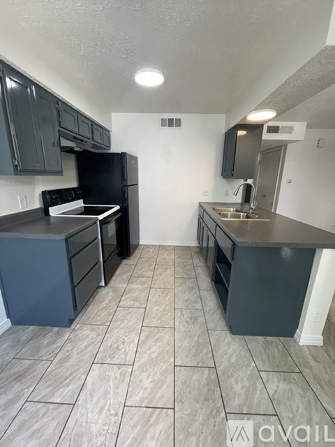 A kitchen with black appliances and grey cabinets.