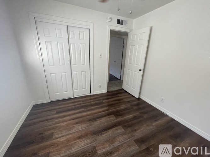 A room with a white door and a wooden floor.
