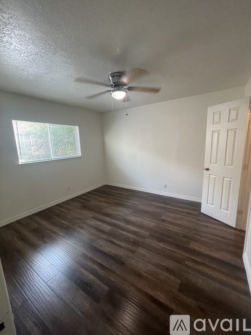 A room with a ceiling fan and wooden flooring.
