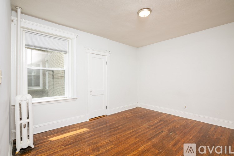A room with wooden floors and a window with blinds.