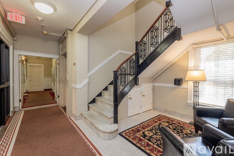 A hallway with a staircase and a rug on the floor.