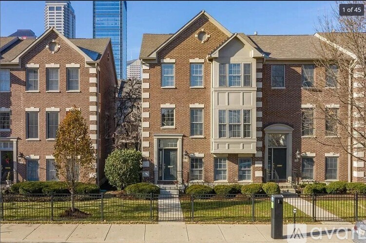 A row of brown brick townhouses with green trees in front.