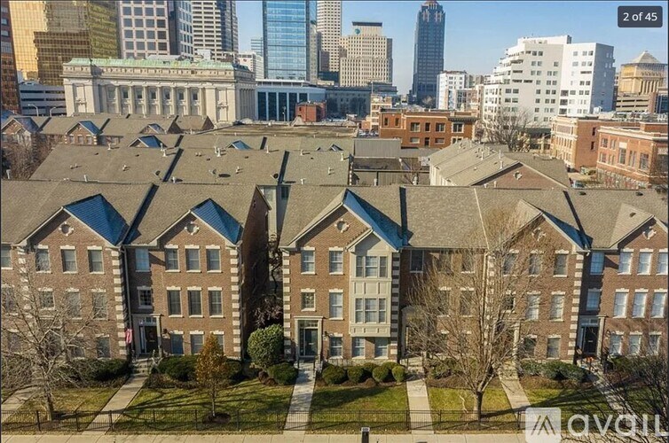 A large building complex with a green lawn in front and a city skyline in the background.