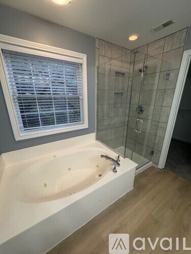 A bathroom with a white bathtub and a window with blinds.