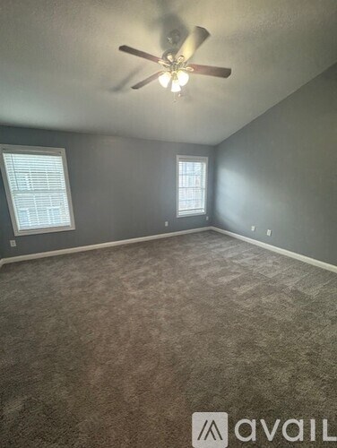 A room with a ceiling fan and two windows.