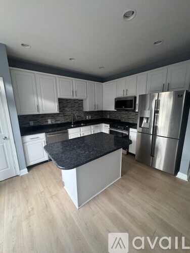 A kitchen with a black granite countertop and stainless steel appliances.