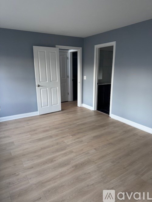 A room with a white door and a wooden floor.
