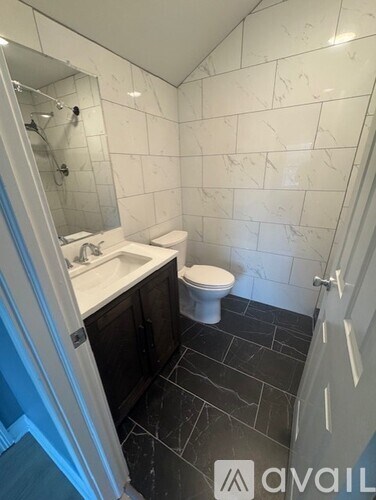 A bathroom with a toilet, sink, and tiled walls.
