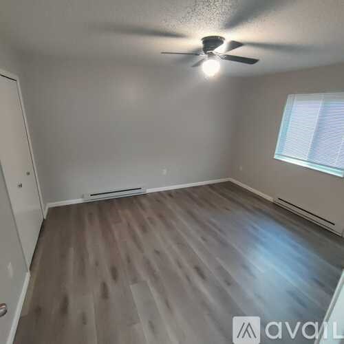 A room with a ceiling fan and a window with blinds.