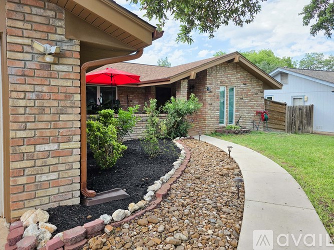 A house with a red umbrella and a garden in front.