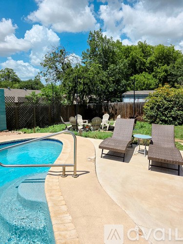 A pool with a metal railing and two lounge chairs.