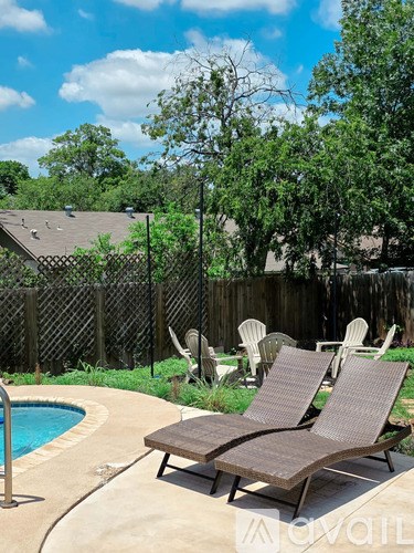 Two lounge chairs are on a patio next to a pool.