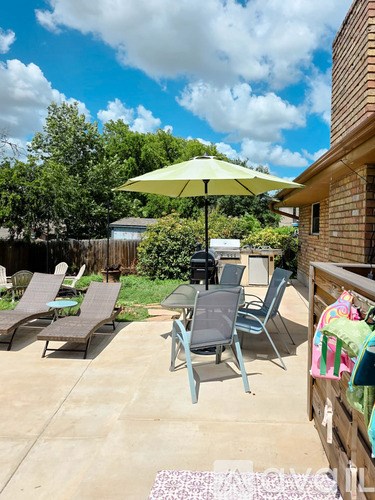 A patio with a table, chairs and an umbrella.