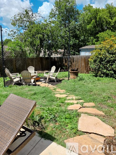 A backyard with a stone pathway leading to a table and chairs.