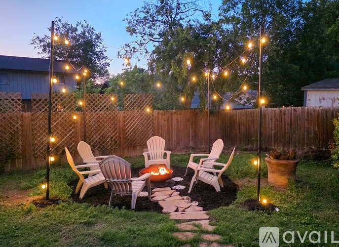 A backyard with a fire pit, chairs, and string lights.