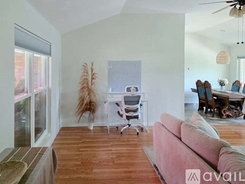 A living room with a pink couch and a white chair.