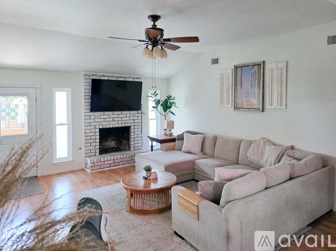 A living room with a grey couch, a coffee table, a fireplace, and a ceiling fan.
