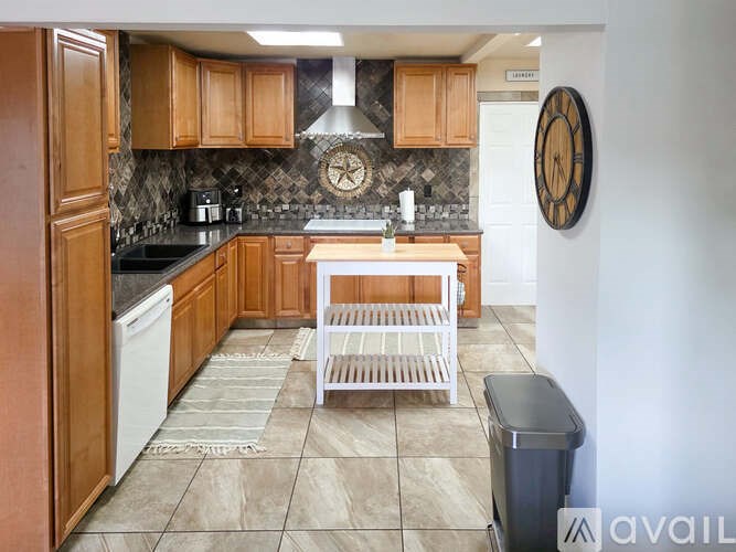 A kitchen with wooden cabinets and a black trash can.