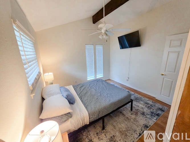 A bedroom with a bed, a ceiling fan, and a window with blinds.