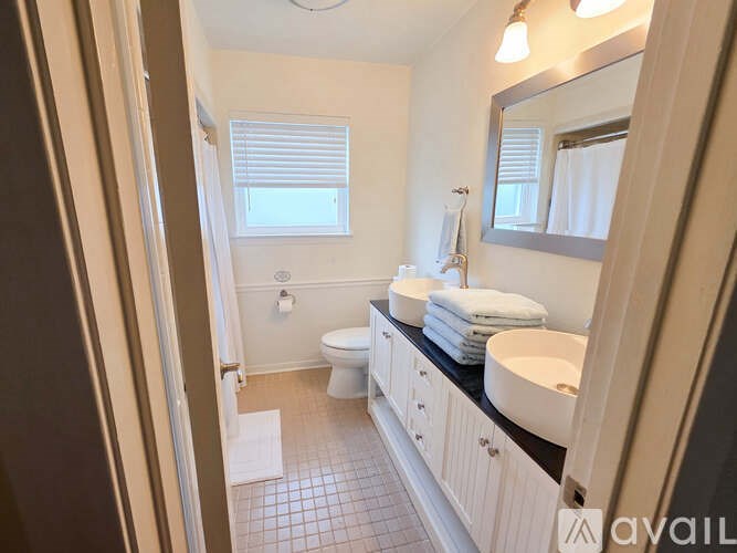 A bathroom with a toilet, sink, and mirror.