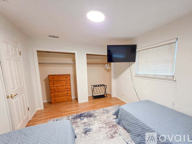 A bedroom with a bed, dresser, and TV.