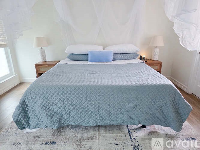 A bed with a blue comforter and white pillows is in the image.