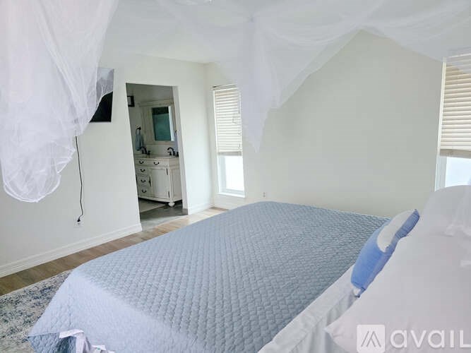 A bedroom with a bed covered in a blue and white comforter.