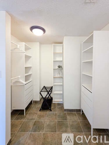 A black bag is on the floor of a white pantry.