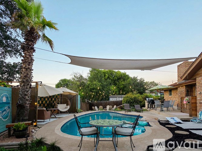 A backyard with a pool and patio furniture.