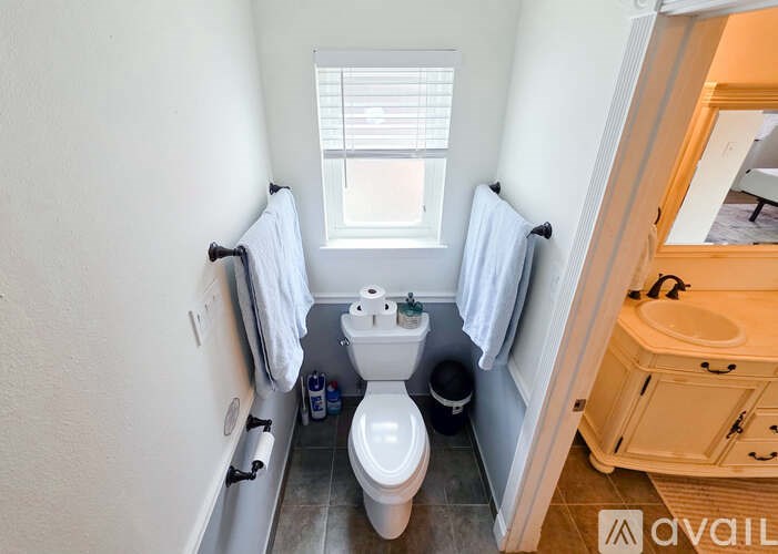 A bathroom with a toilet, sink, and a window.