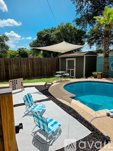 A pool with a white umbrella and blue and white striped chairs.