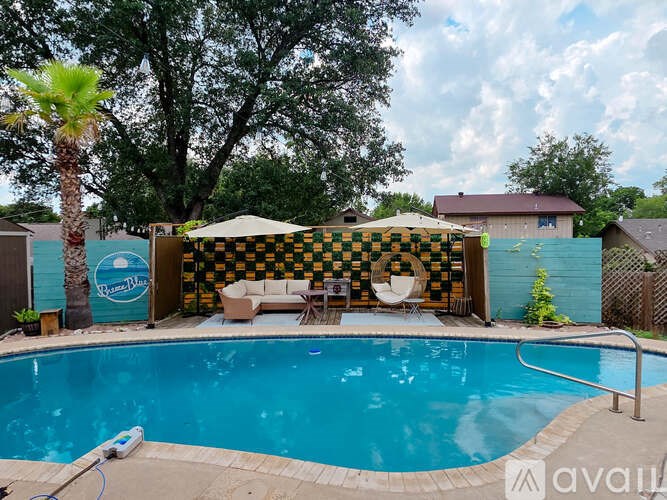 A pool with a striped umbrella and a striped couch.