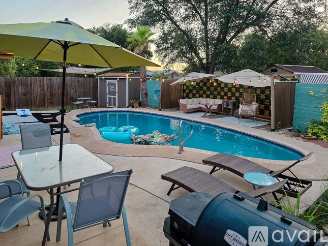 A backyard with a pool and a table with chairs.