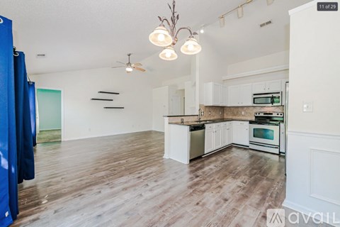 A kitchen with white cabinets and a wooden floor.