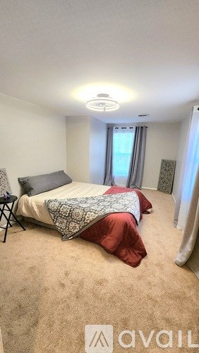 A bedroom with a bed and a carpeted floor.