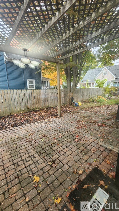 A patio with a roof and a tree in the background.