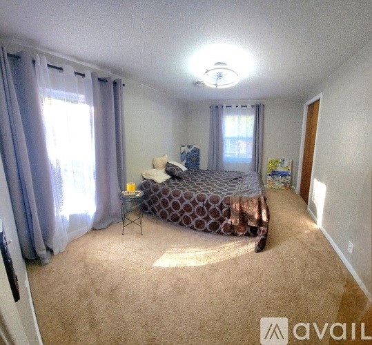 A bedroom with a bed, a chair, and a window with curtains.