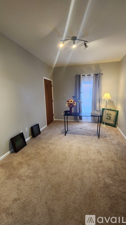 A room with a carpeted floor and a table with chairs.