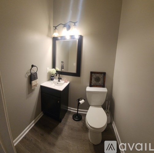 A bathroom with a toilet, sink, and mirror.