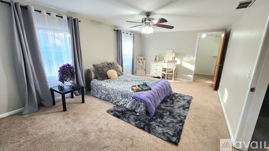 A bedroom with a bed, a chair, and a table with a vase of flowers on it.