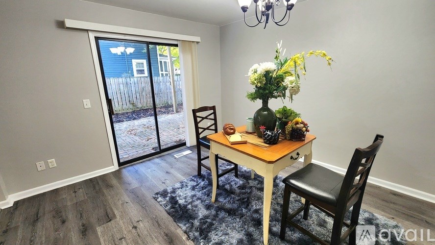 A dining room with a table, chairs, and a vase of flowers.