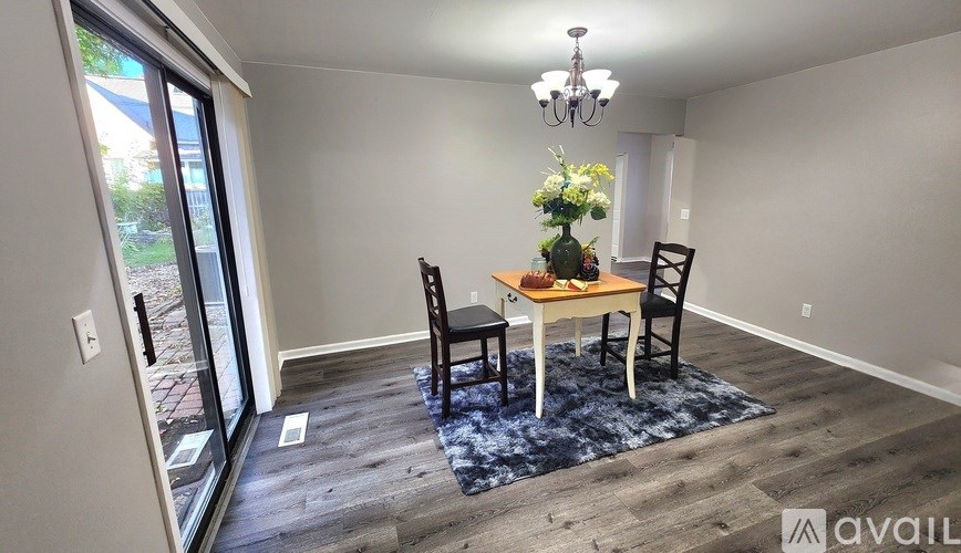 A dining room with a table set for two and a chandelier.