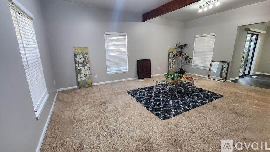 A room with a carpet, a rug, and a painting on the wall.