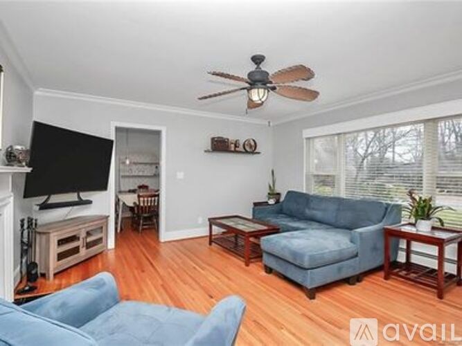 A living room with a blue couch and a ceiling fan.